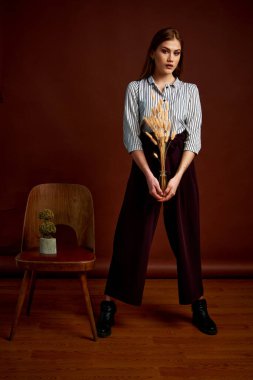 Genç bağımsız kadının minimalizm stili klasik stüdyo fotoğraf seti. Klasik takım elbiseli, siyah ayakkabılı ve gri ceketli güzel bir bayan. Klasik sandalye. Kadın kıyafetleri. Şık kıyafetler..