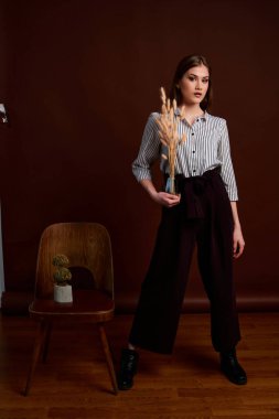 Genç bağımsız kadının minimalizm stili klasik stüdyo fotoğraf seti. Klasik takım elbiseli, siyah ayakkabılı ve gri ceketli güzel bir bayan. Klasik sandalye. Kadın kıyafetleri. Şık kıyafetler..