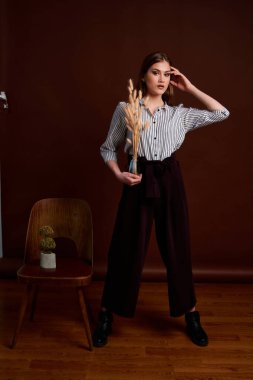 Genç bağımsız kadının minimalizm stili klasik stüdyo fotoğraf seti. Klasik takım elbiseli, siyah ayakkabılı ve gri ceketli güzel bir bayan. Klasik sandalye. Kadın kıyafetleri. Şık kıyafetler..