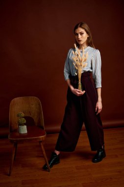 Genç bağımsız kadının minimalizm stili klasik stüdyo fotoğraf seti. Klasik takım elbiseli, siyah ayakkabılı ve gri ceketli güzel bir bayan. Klasik sandalye. Kadın kıyafetleri. Şık kıyafetler..