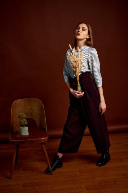 Genç bağımsız kadının minimalizm stili klasik stüdyo fotoğraf seti. Klasik takım elbiseli, siyah ayakkabılı ve gri ceketli güzel bir bayan. Klasik sandalye. Kadın kıyafetleri. Şık kıyafetler..