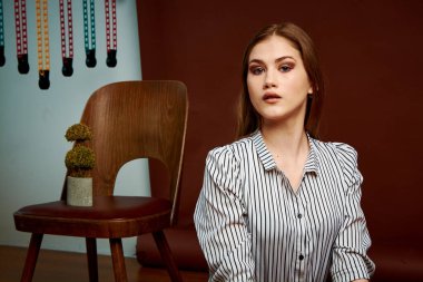 Genç bağımsız kadının minimalizm stili klasik stüdyo fotoğraf seti. Klasik takım elbiseli, siyah ayakkabılı ve gri ceketli güzel bir bayan. Klasik sandalye. Kadın kıyafetleri. Şık kıyafetler..