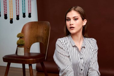 Genç bağımsız kadının minimalizm stili klasik stüdyo fotoğraf seti. Klasik takım elbiseli, siyah ayakkabılı ve gri ceketli güzel bir bayan. Klasik sandalye. Kadın kıyafetleri. Şık kıyafetler..