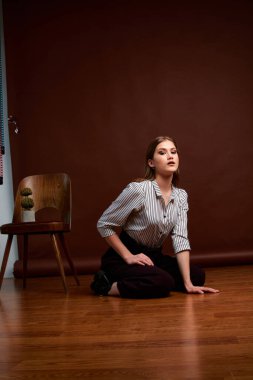 Genç bağımsız kadının minimalizm stili klasik stüdyo fotoğraf seti. Klasik takım elbiseli, siyah ayakkabılı ve gri ceketli güzel bir bayan. Klasik sandalye. Kadın kıyafetleri. Şık kıyafetler..