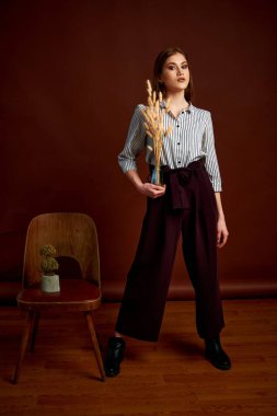 Genç bağımsız kadının minimalizm stili klasik stüdyo fotoğraf seti. Klasik takım elbiseli, siyah ayakkabılı ve gri ceketli güzel bir bayan. Klasik sandalye. Kadın kıyafetleri. Şık kıyafetler..
