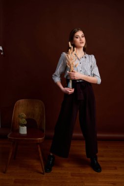 Genç bağımsız kadının mininalizm stili klasik stüdyo fotoğraf seti. Klasik takım elbiseli, siyah ayakkabılı ve gri ceketli güzel bir bayan. Klasik sandalye. Kadın kıyafetleri. Şık kıyafetler..