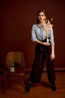 Genç bağımsız kadının minimalizm stili klasik stüdyo fotoğraf seti. Klasik takım elbiseli, siyah ayakkabılı ve gri ceketli güzel bir bayan. Klasik sandalye. Kadın kıyafetleri. Şık kıyafetler..