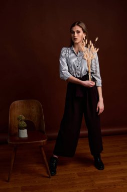 Genç bağımsız kadının minimalizm stili klasik stüdyo fotoğraf seti. Klasik takım elbiseli, siyah ayakkabılı ve gri ceketli güzel bir bayan. Klasik sandalye. Kadın kıyafetleri. Şık kıyafetler..