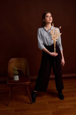 Genç bağımsız kadının minimalizm stili klasik stüdyo fotoğraf seti. Klasik takım elbiseli, siyah ayakkabılı ve gri ceketli güzel bir bayan. Klasik sandalye. Kadın kıyafetleri. Şık kıyafetler..