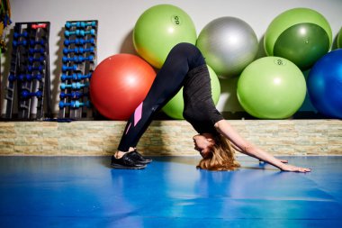 Siyah spor giysili zayıf atletik genç kadın spor jimnastik salonlarında spor yapıyor. Kadın antrenmanı. Spor salonunda spor topları. Spor salonunda iyi fiziksel kondisyon ve düzenli eğitim kavramı.