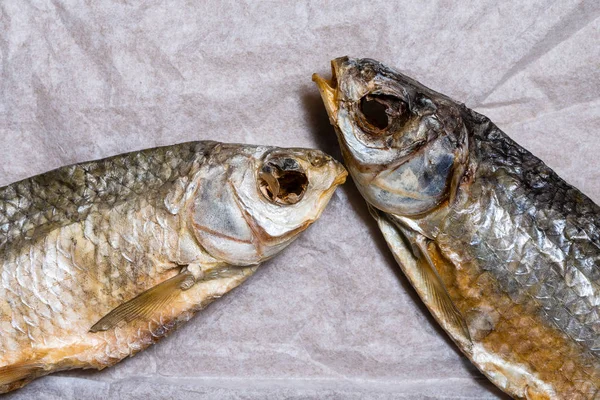 Två torkade fiskar på gammalt skrynkligt papper. Närbild. Topptittare. Se — Stockfoto
