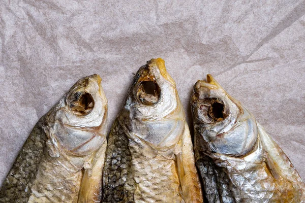 Huvuden på tre torkade fiskar på gammalt skrynkligt papper. Närbild. T — Stockfoto