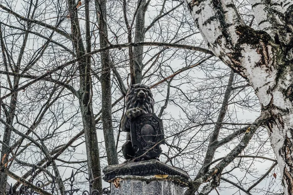 Majestätische Löwenstatue mit Schild auf einem Hintergrund aus Bäumen und — Stockfoto