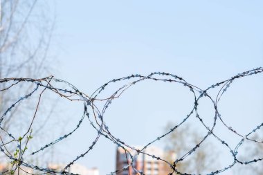 Konut binalarının bir kısmının bulanık arka planında dikenli tel var. Tecrit kavramı. Seçici odak.