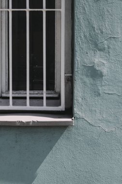 Mavi duvardaki eski pencere. Güneşli bir gün. Pencerenin gölgesi.