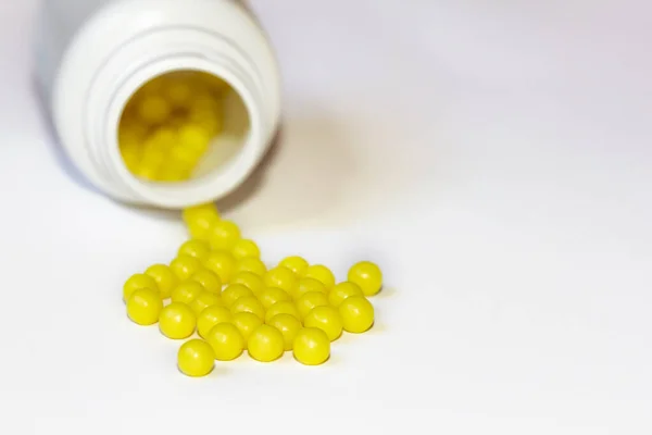Round yellow vitamin C tablets on a white background. Ascorbic acid close-up. Vitamin C for the treatment and prevention of colds. Virus protection.