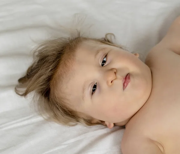 Retrato de un bebé con parálisis cerebral acostado en la cama. Niño con necesidades especiales. Primer plano de niño discapacitado. Niño discapacitado . — Foto de Stock