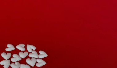 Kırmızı arka planda birçok el yapımı beyaz tekstil kalbi. 