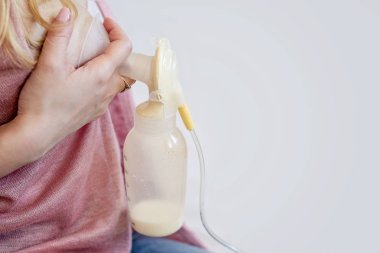 Genç anne tek başına anne sütü pompası kullanıyor.