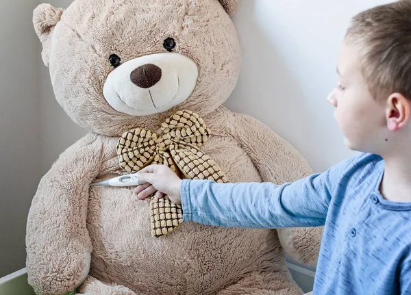 Kleuterschooljongen zorgt voor zijn zieke teddybeer.. — Stockfoto