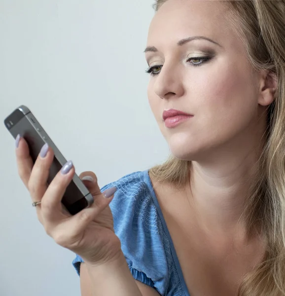 Retrato de una joven atractiva mirando por teléfono . — Foto de Stock