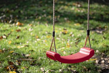 Sonbaharda parktaki çocuk parkına boş kırmızı salıncak