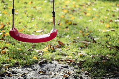 Sonbaharda parktaki çocuk parkına boş kırmızı salıncak