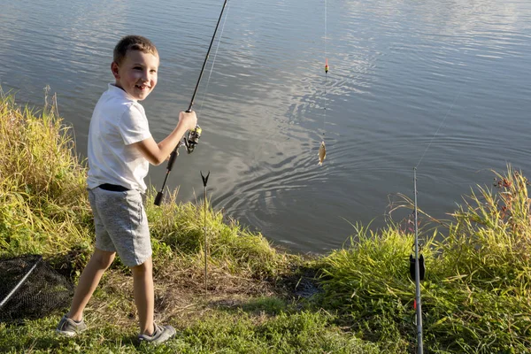 Un chico feliz pescó un pez. Niño pescando en un lago — Foto de Stock