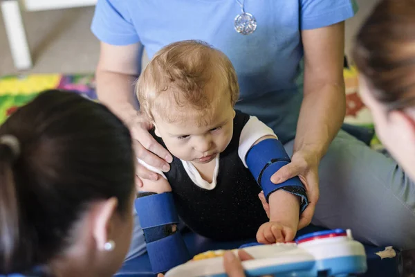 Çocuk terapi merkezinde fizyoterapi üzerine beyin felci geçirmiş bir çocuğun portresi. Özürlü çocuk rehabilitasyon merkezinde fizyoterapistlerle egzersiz yaparak terapi görüyor..