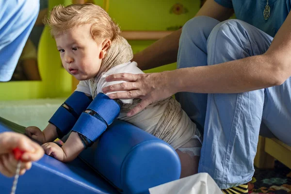 Çocuk terapi merkezinde fizyoterapi üzerine beyin felci geçirmiş bir çocuğun portresi. Özürlü çocuk rehabilitasyon merkezinde fizyoterapistlerle egzersiz yaparak terapi görüyor..