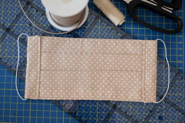 Dikiş aksesuarlarıyla el yapımı bej kumaş pamuk yüz maskesi. Tükürük, öksürük, toz, kirlilik, virüs, bakteri, COVID-19 'a karşı koruma. 