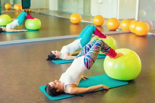 Deux gymnastes ayant des exercices pour les hanches et les fesses en utilisant une balle fraîche . — Photo