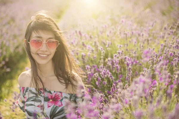 Lavendelfeld. lächelnde Frau, die durch blühende Blumen sitzt. — Stockfoto