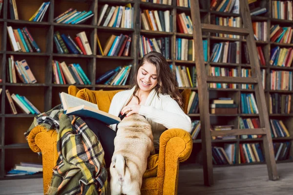 Молодая студентка читает книги в домашней библиотеке — стоковое фото