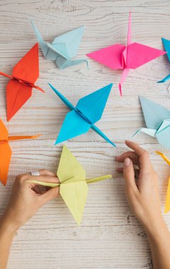 Ahşap masa üzerinde tutan güzel origami kuşlar kadın el. Üstten Görünüm. Dikey kompozisyon