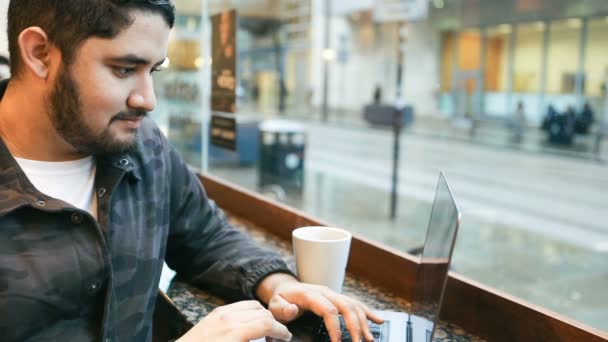 Joven morena latino hispano chico está utilizando la computadora sentado en la cafetería. Imágenes de vídeo — Vídeos de Stock