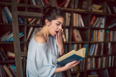 büyülenmiş bir kız kitap haline hayretle görünüyor. Bir beklenmeyen entrika hikaye şok edici.