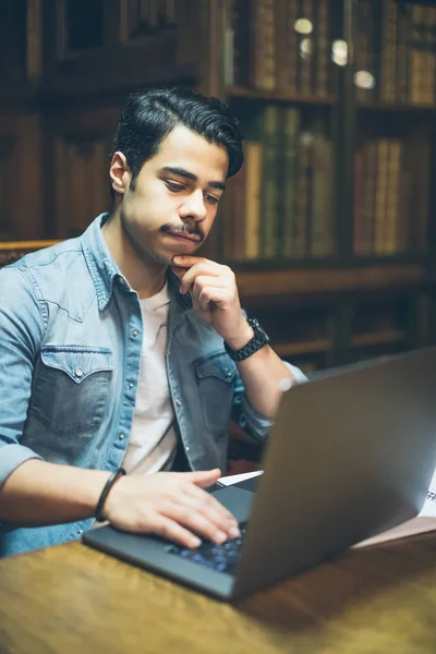 Smart junger arabischer Mann arbeitet in Bibliothek mit Computer — Stockfoto