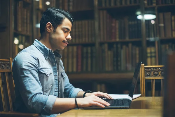 Education in Europe. arabic young handsome working in old library. Horizontal composition. View from side profile