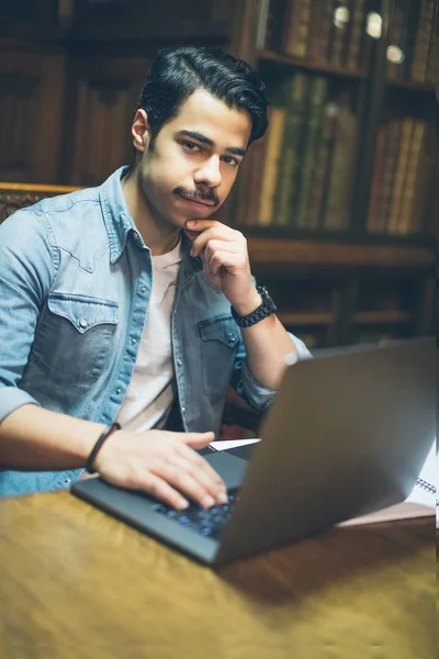 Smiling young arabic guy using laptop. education abroad in europe