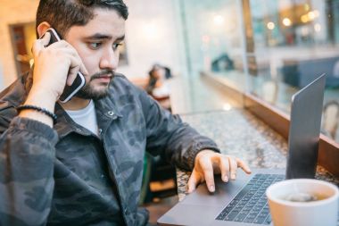 bir telefon ve kafede bir bilgisayar ile bir genç Panama işadamı çalışır