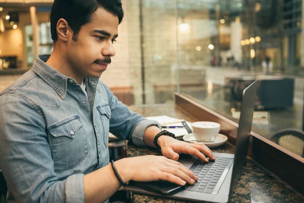 Young arabic guy using computer in cafe. Modern lifestyle photo