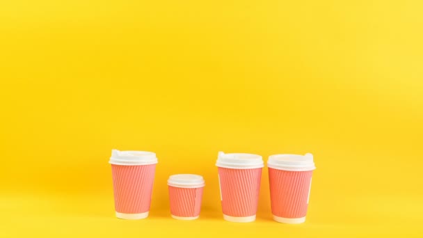 Pink and yellow coffee cups. Video footage timelapse stop motion. Funny changing size movie. Bright cheerful yellow background. — Stock Video