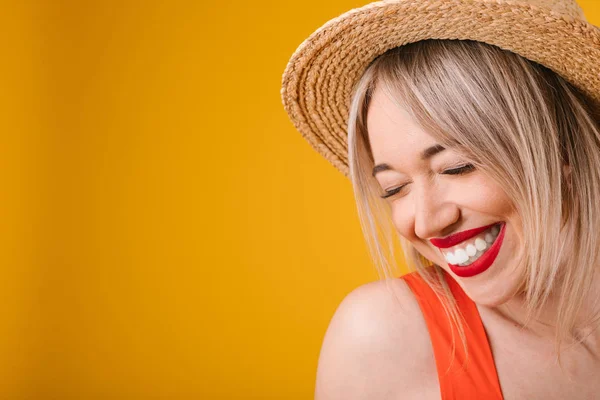 Adrable sonriente confundido avergonzado mujer rubia modesta en sombrero de paja. Ambiente cálido de verano fondo amarillo. Emociones felices encantadoras —  Fotos de Stock