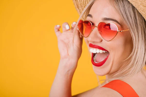 Vzrušená radostné šťastné blond žena portrét na žlutém podkladu. Růžové brýle ve tvaru srdce. — Stock fotografie