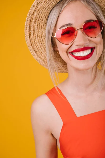 Adorable portrait de femme blonde souriante sur fond jaune. Lunettes de soleil roses en forme de coeur. Moments de bonne humeur estivale — Photo