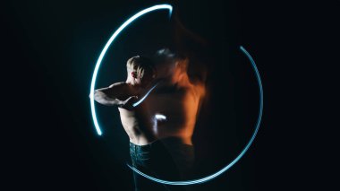 Çıplak gövdeli genç adam. Uzun pozlama karanlıkta daireler çizer. Duyguların duygusal metaforik ifadesi. 