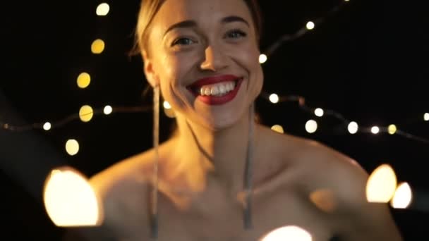 Gyönyörű Szőke Mosolygós Boldog Fekete Háttérrel Újévi Hangulatvilágítás Kézi Lélegeztető — Stock videók