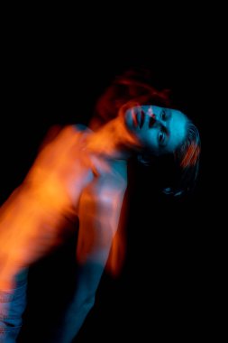 Genç tiyatrocunun sanatsal portresi nostalji ve üzüntüyle kameraya bakıyor. Mavi ve turuncu tamamlayıcı renkler. Yaratıcı uzun pozlama fotoğrafları serisi mecazi duygular