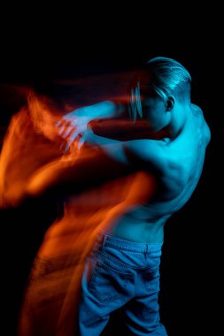 Sırt ve omurga portresi genç sarışın dansçı. Kıvranmak, direnmek, vücut hareketlerini reddetmek. Siyah arka plan. Yaratıcı uzun pozlama fotoğrafları serisi kinayeli mecazi duygu gösterimi. 